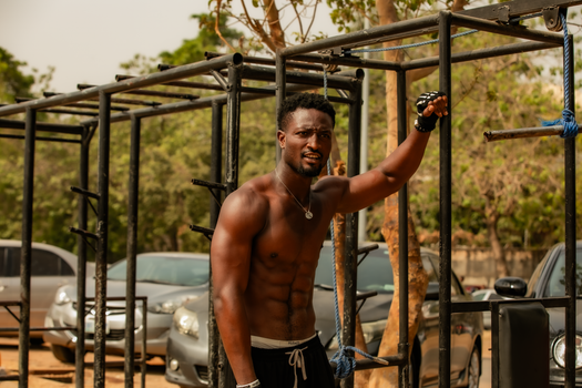 Athletic black man working out on outdoor monkey bars for fitness.