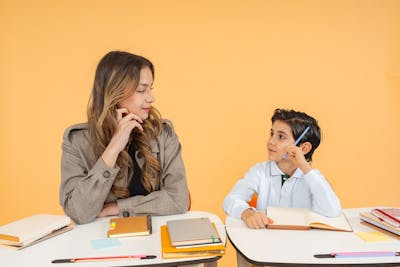 A teacher and student having an attentive conversation about learning goals, with notebooks open
