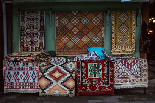 Free A vibrant collection of traditional woven rugs displayed outdoors in a market setting. Stock Photo