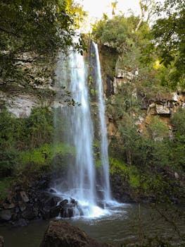 A majestic waterfall cascading down rocky cliffs, surrounded by lush greenery.