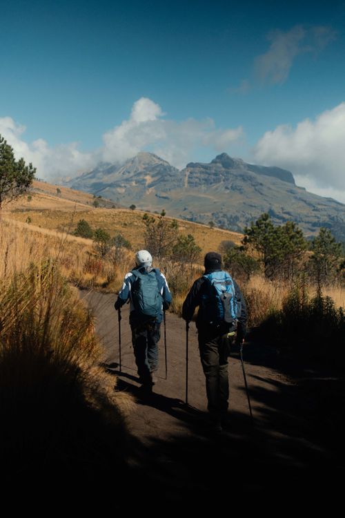 Free Two hikers explore a picturesque mountain trail under clear skies. Stock Photo