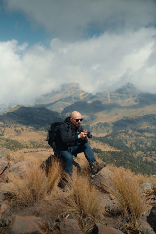 Free A photographer capturing breathtaking views atop a rocky mountain with a camera. Stock Photo
