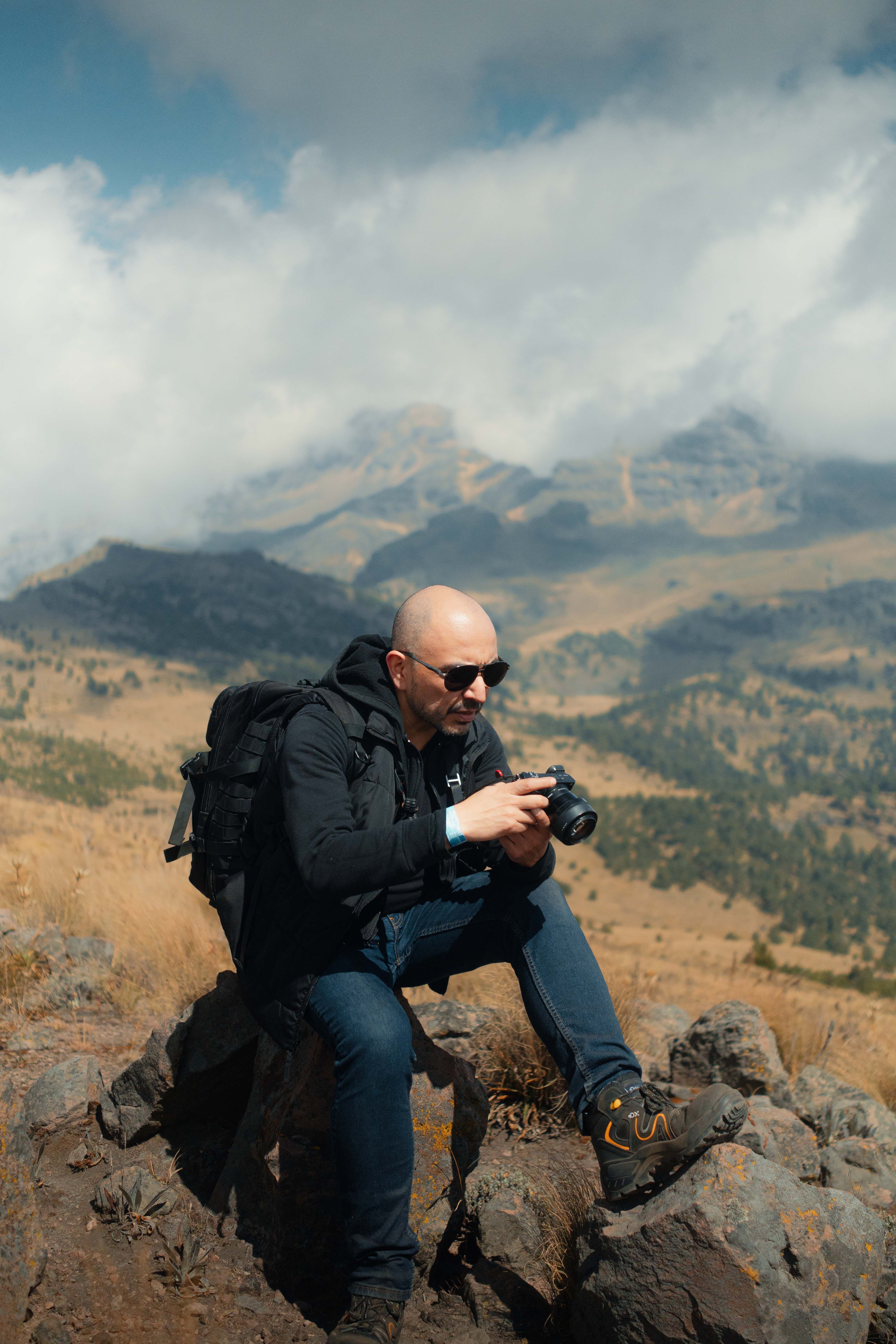 An adventurous photographer takes a shot from a rocky overlook in a mountainous region.