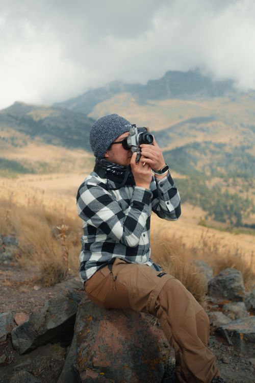 Free A person takes photographs of a mountainous landscape, showcasing outdoor adventure. Stock Photo