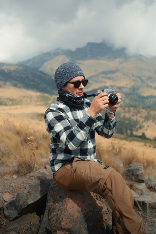 Free A man takes photos in a beautiful mountain setting, showcasing nature's splendor. Stock Photo