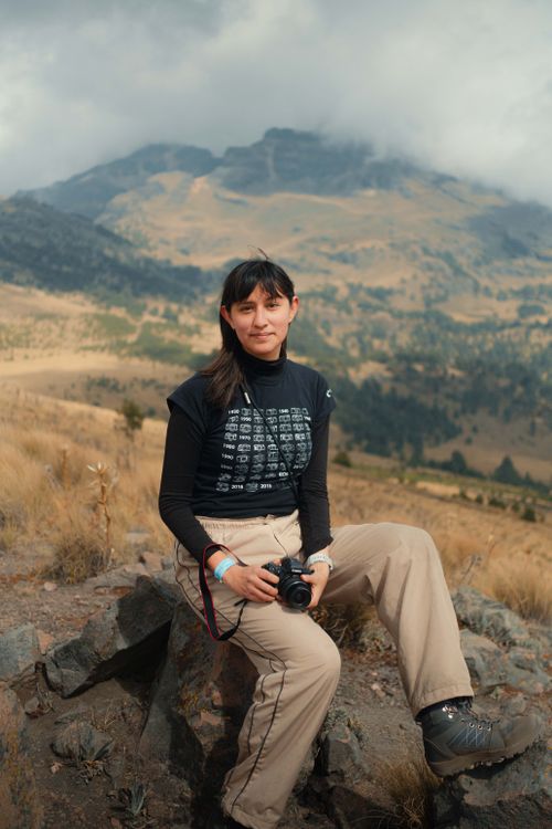 Free A female photographer takes a break with her camera on a mountain, highlighting the beauty of nature. Stock Photo