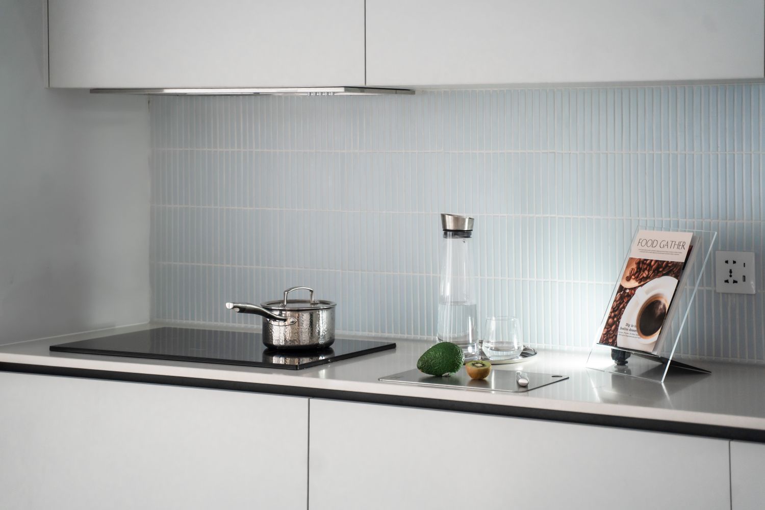 A black induction cooktop with a pot on a white kitchen bench
