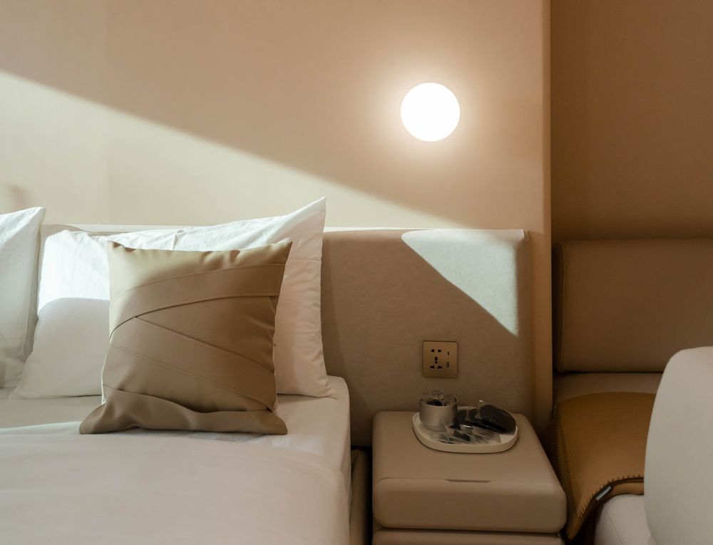 Warm beige hotel suite with a made bed and bedside table — photo by Alley Chien on Pexels