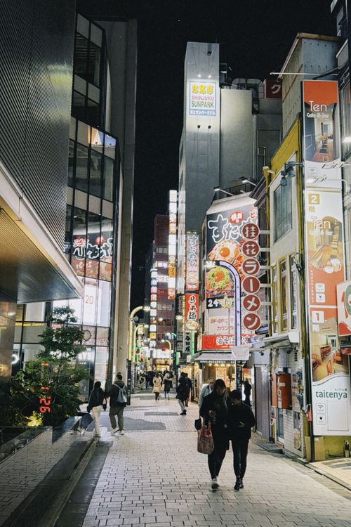 Free Nighttime in bustling Shibuya, Tokyo with bright city lights and people walking along the street. Stock Photo
