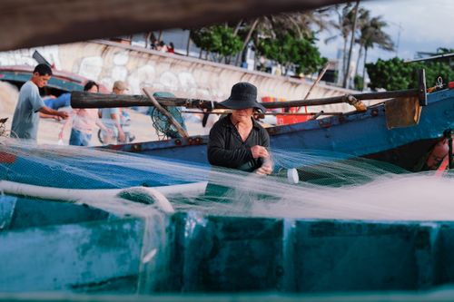 Free A fisherman deftly handling nets on a boat in Vũng Tàu, capturing the essence of local life. Stock Photo