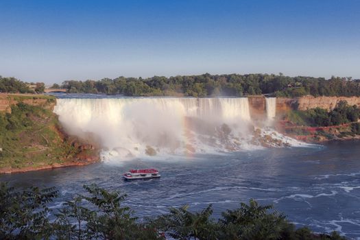 Stunning view of Niagara Falls with a vibrant rainbow and tour boat.