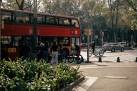 Busy street scene in Ciudad de México featuring a bright red double-decker bus and cyclists at a crosswalk.