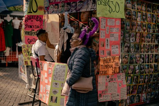 A bustling market stall in Mexico City offering face painting and temporary tattoos.
