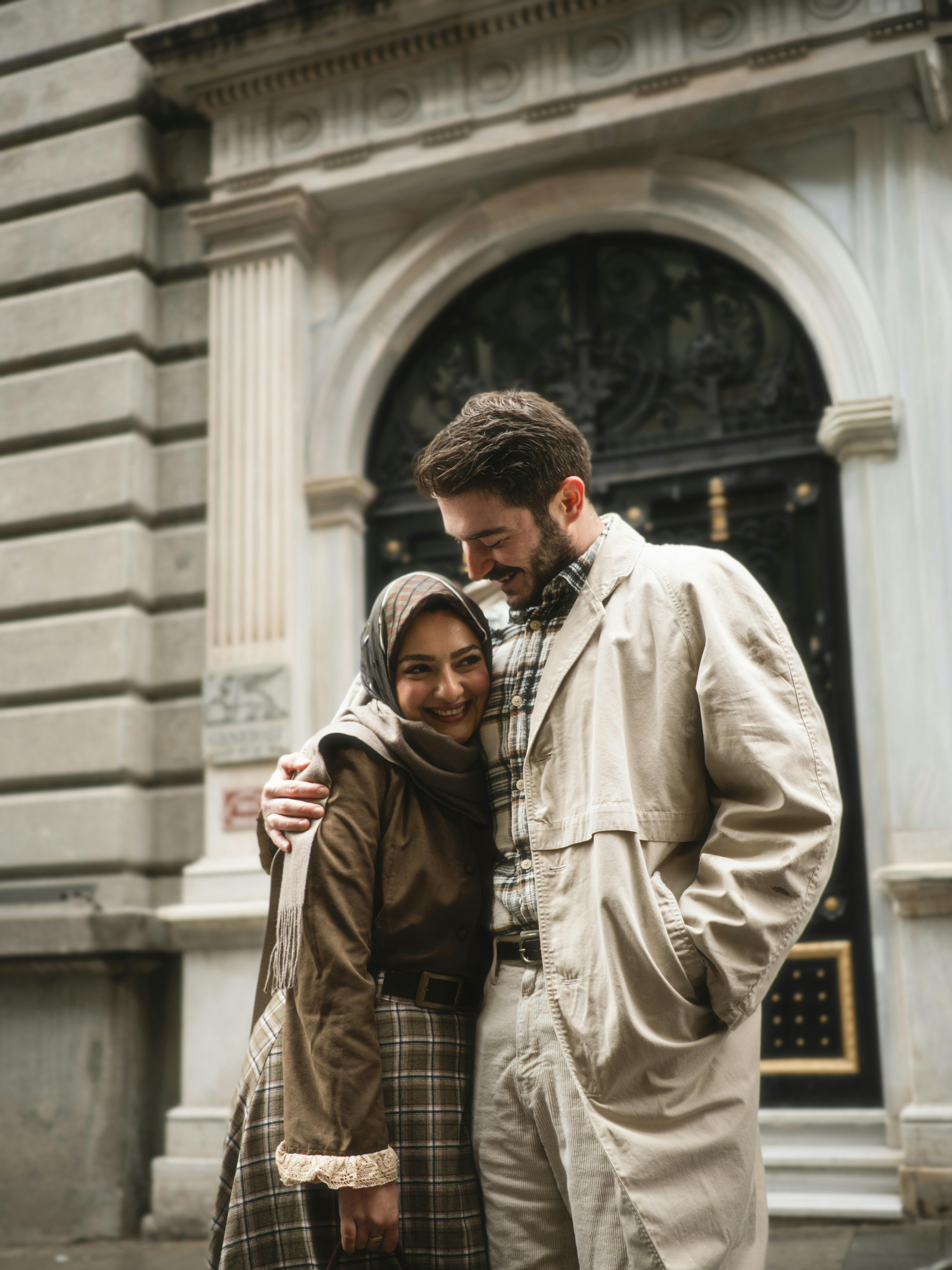 Happy couple embracing in front of an ornate building entrance.