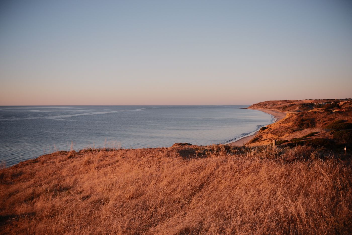 Rocky coastal cliff overlooking a calm ocean during sunset