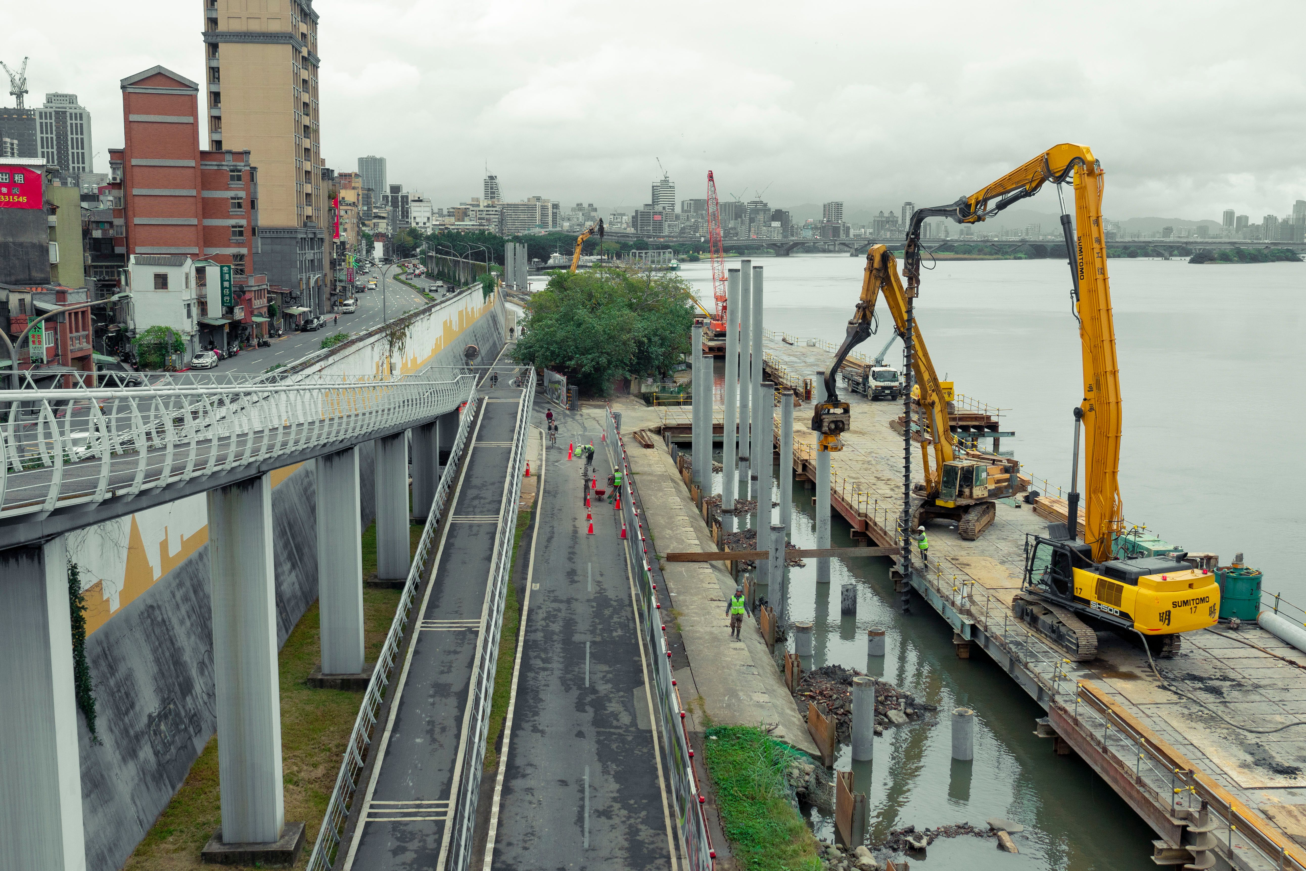 Riverfront construction site with machinery and workers