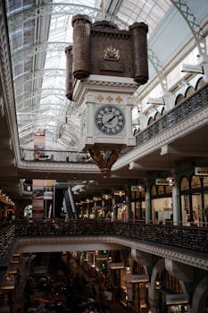 Beautiful view of a historic clock hanging in a bustling grand arcade shopping mall.
