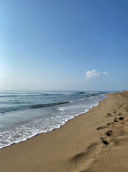 Free Peaceful sandy beach with gentle waves under a clear blue sky, inspiring relaxation. Stock Photo