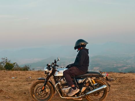 A biker on a motorcycle enjoys a serene mountain view during daytime.