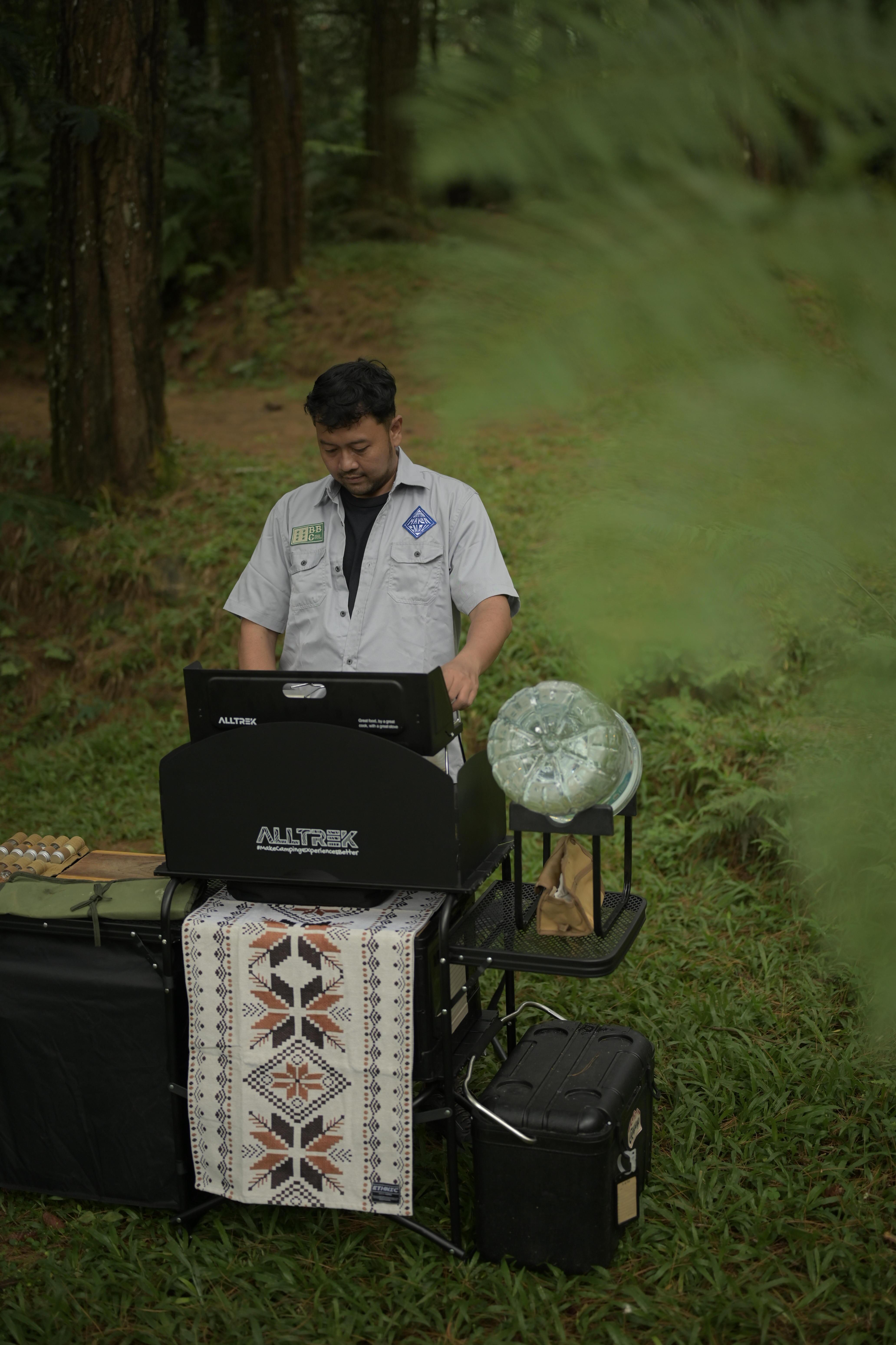Man setting up an outdoor cooking station in a forest in West Java, Indonesia.
