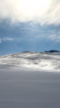 Stunning winter scene of snow-covered mountains under a bright sky in Niğde, Türkiye.