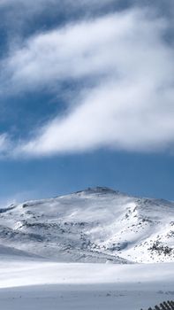 Peaceful winter scene of a snow-covered mountain under a bright blue sky in Niğde, Türkiye.