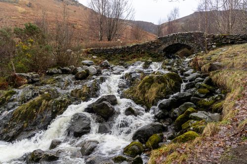 Free Stone bridge over a cascading stream in winter, set in the English countryside. Stock Photo