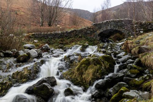 Free A picturesque stone bridge over a waterfall in the English countryside during winter. Stock Photo