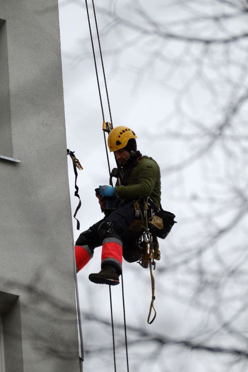 Tehničar za pristup užetom u sigurnosnoj opremi radi na fasadi zgrade