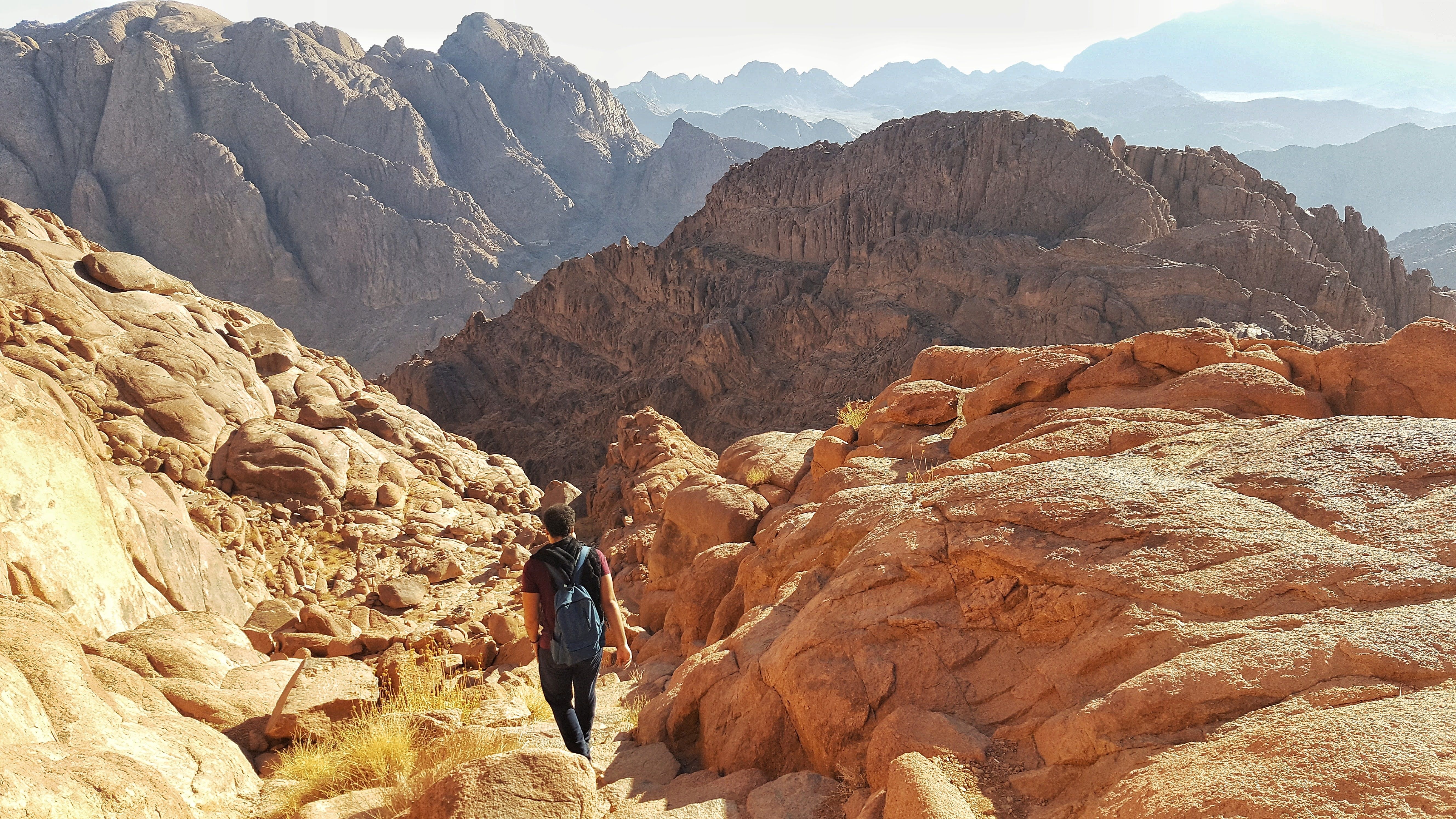 Hiker walking through the rugged mountains of South Sinai, capturing the vast landscape.
