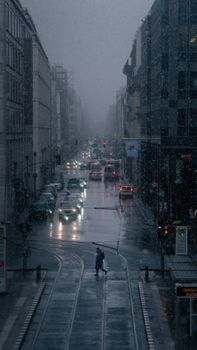 A winter evening in Berlin with cars and a pedestrian amid falling snow and city lights.