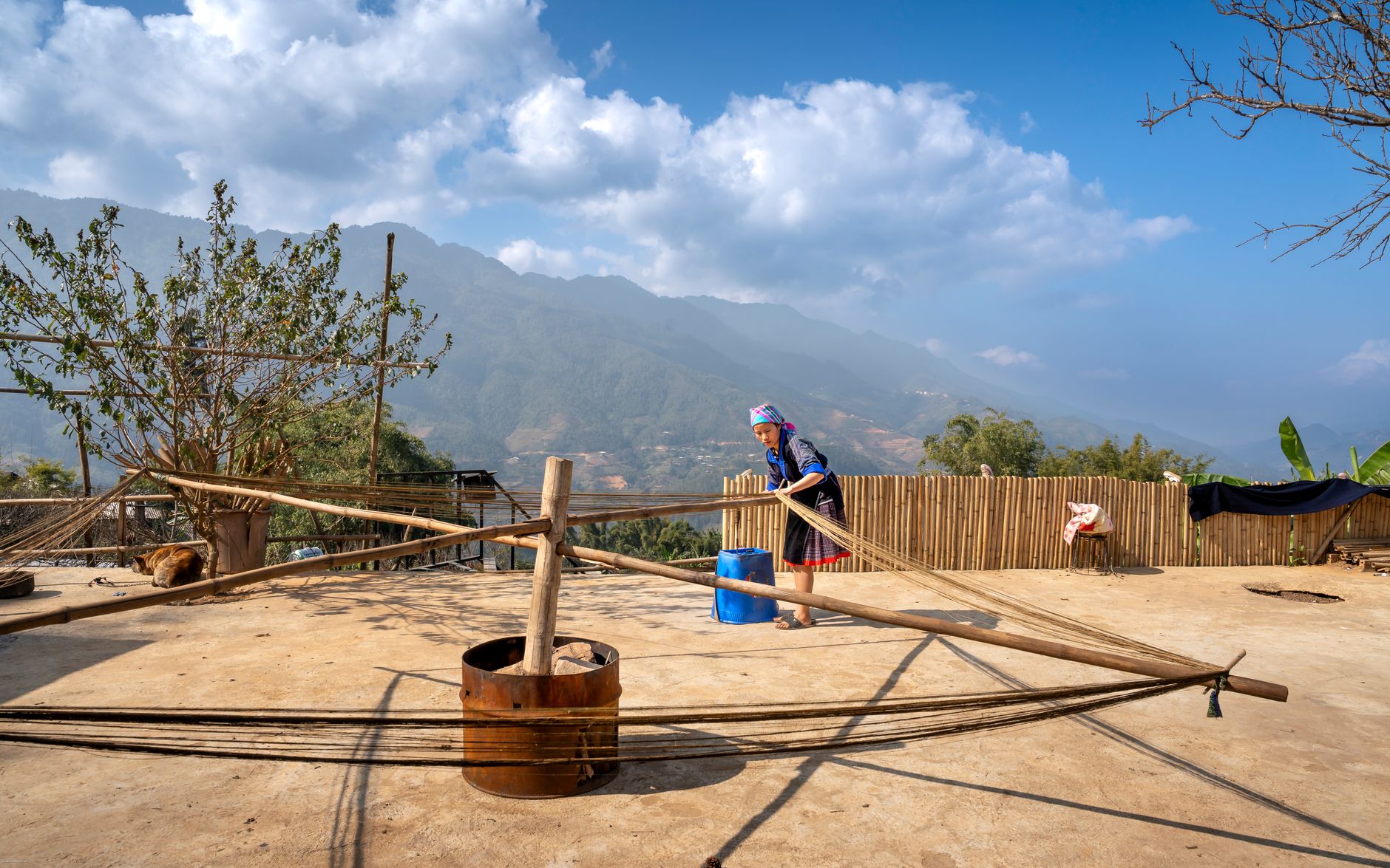 A woman weaving outdoors in the scenic highlands of Northern Vietnam, showcasing traditional textile methods.