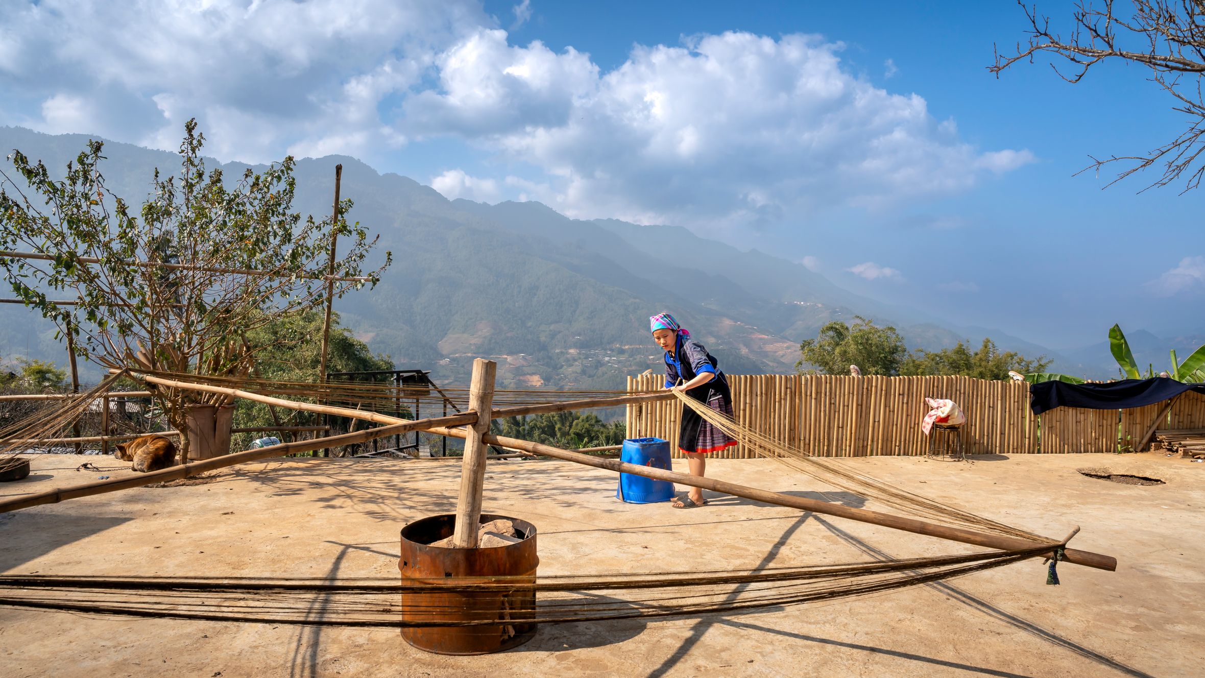 A woman weaving outdoors in the scenic highlands of Northern Vietnam, showcasing traditional textile methods.