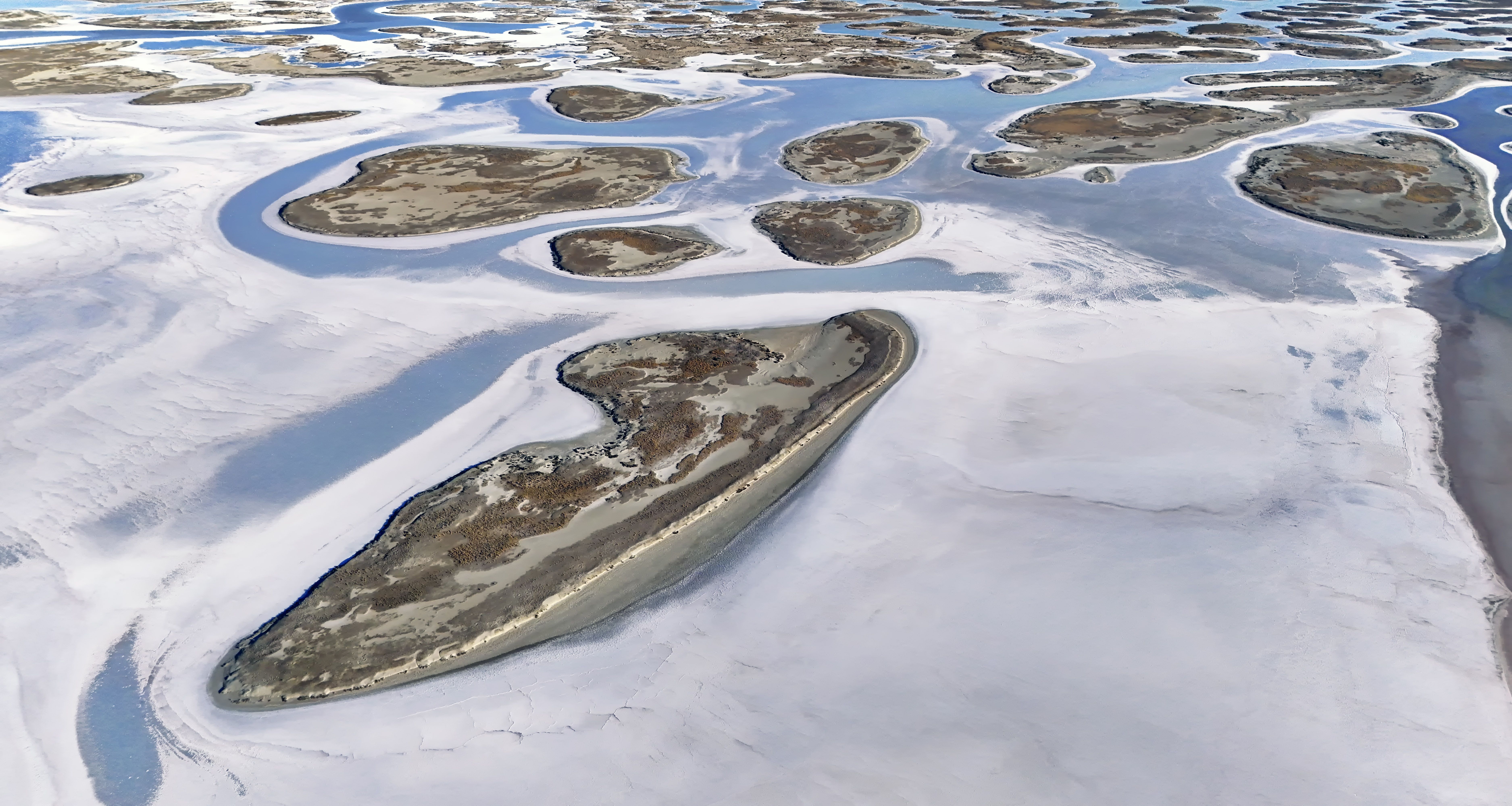 Aerial landscape of salt flats and blue lagoons in spring. Stunning natural patterns.