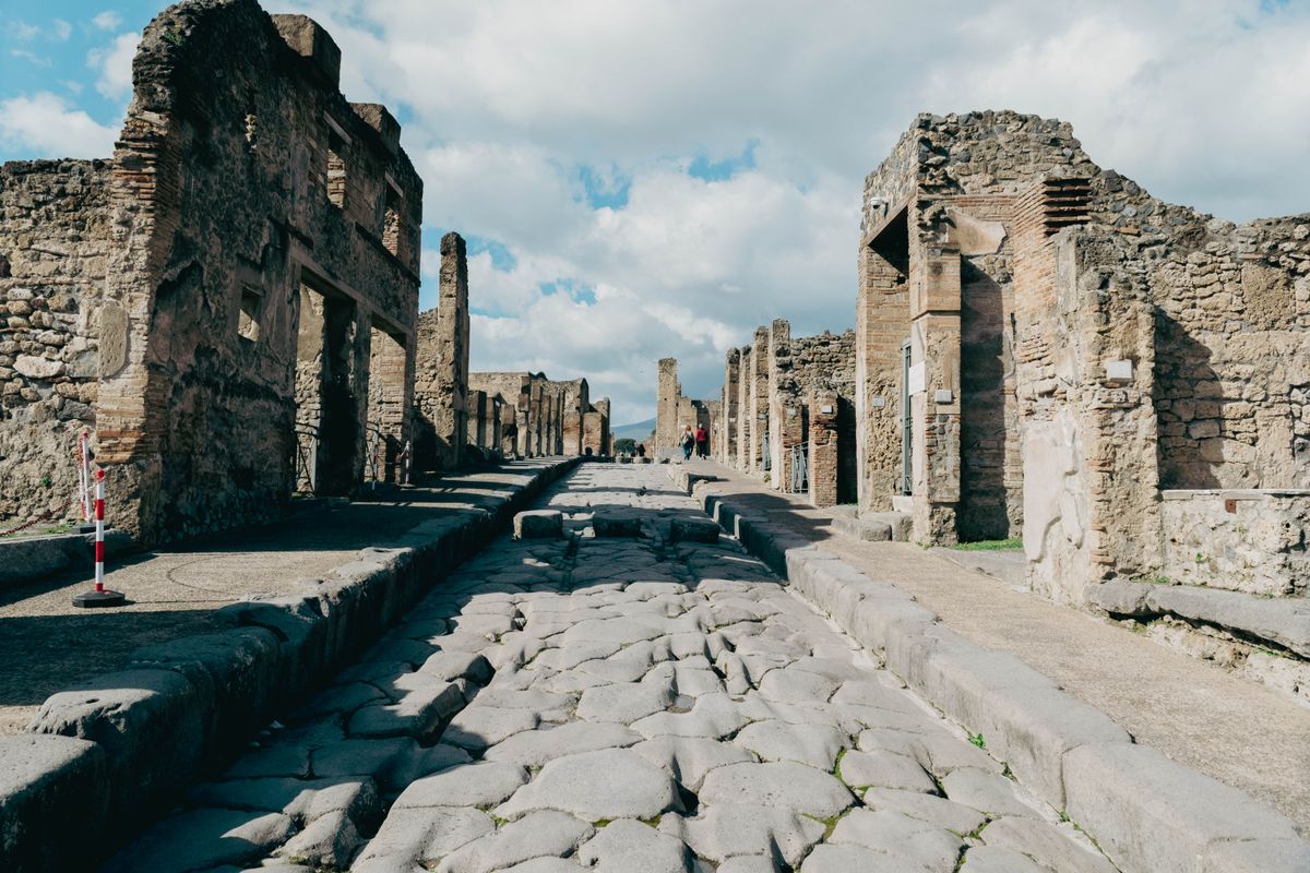 Pompeii's Via dell'Abbondanza — cart ruts and doorways sealed by Vesuvius in 79 AD.