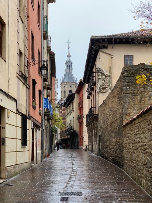 Free A quaint street in Vitoria-Gasteiz showcasing historic architecture and a church tower on a rainy day. Stock Photo