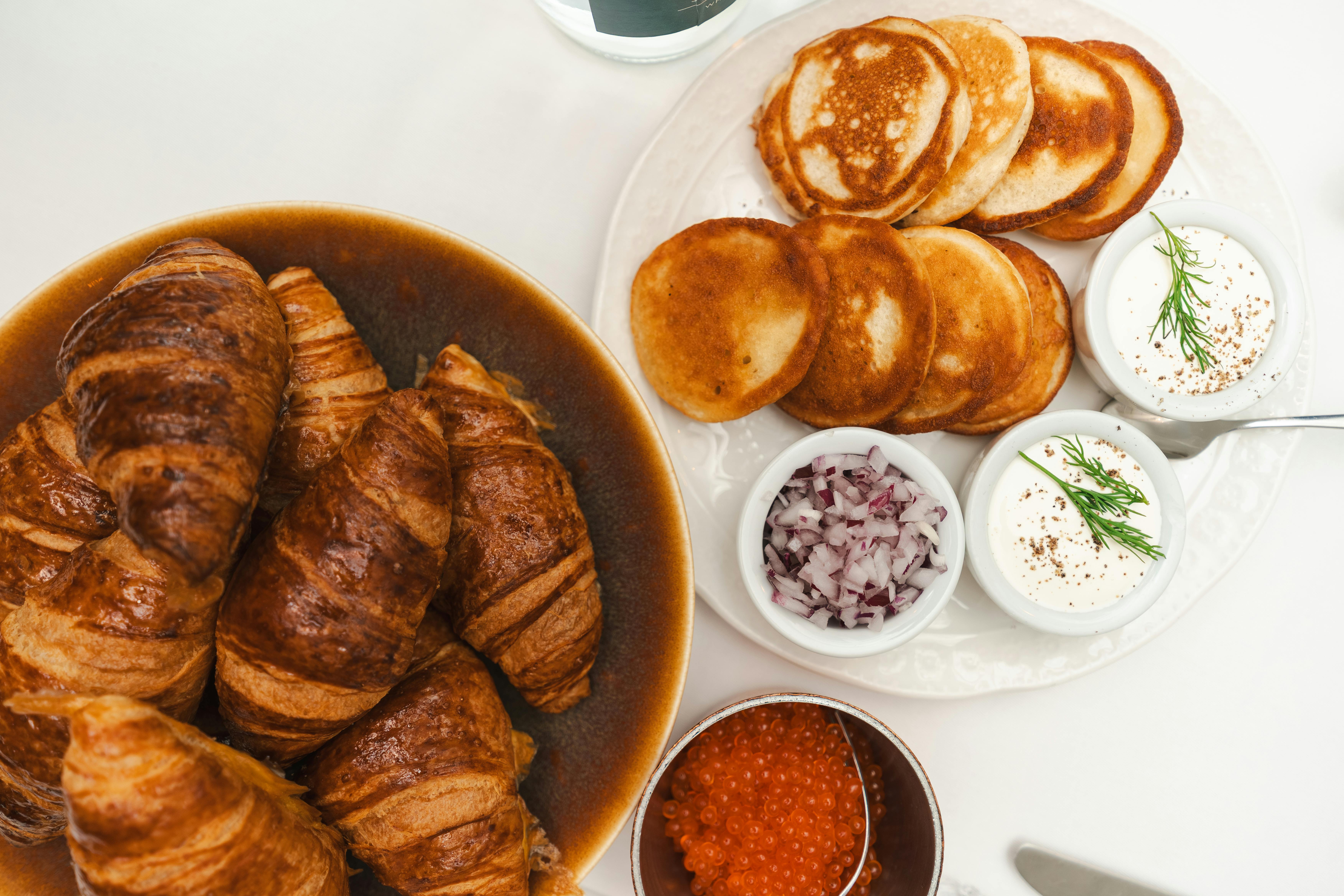 A mouth-watering breakfast spread featuring croissants, pancakes, and various toppings, perfect for a delightful morning meal.