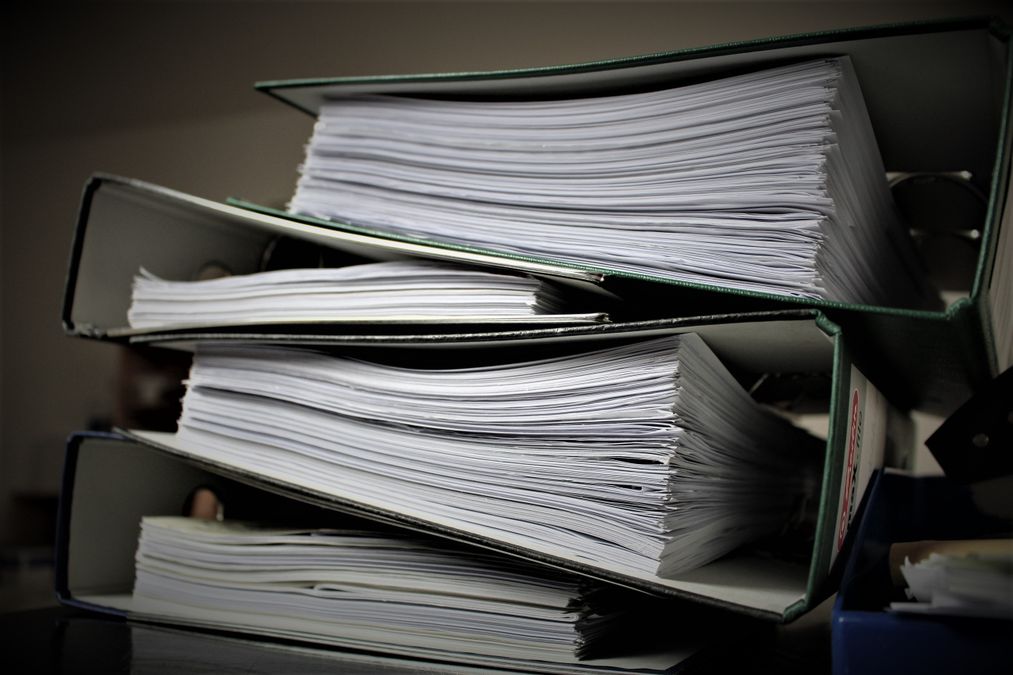 Pilha de pastas e fichários organizados com documentos arquivados