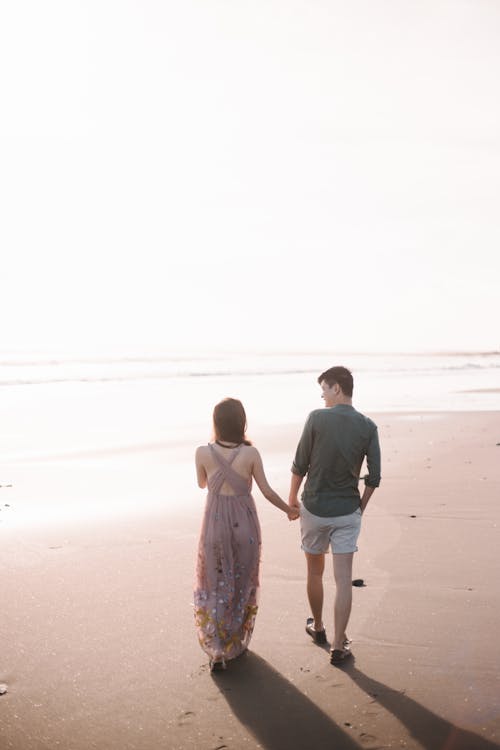 Free Man and Woman Walking on Beach Stock Photo