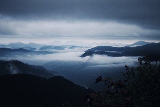 A dramatic view of misty mountains in Đà Lạt, Vietnam, showcasing layers of hills under cloudy skies.