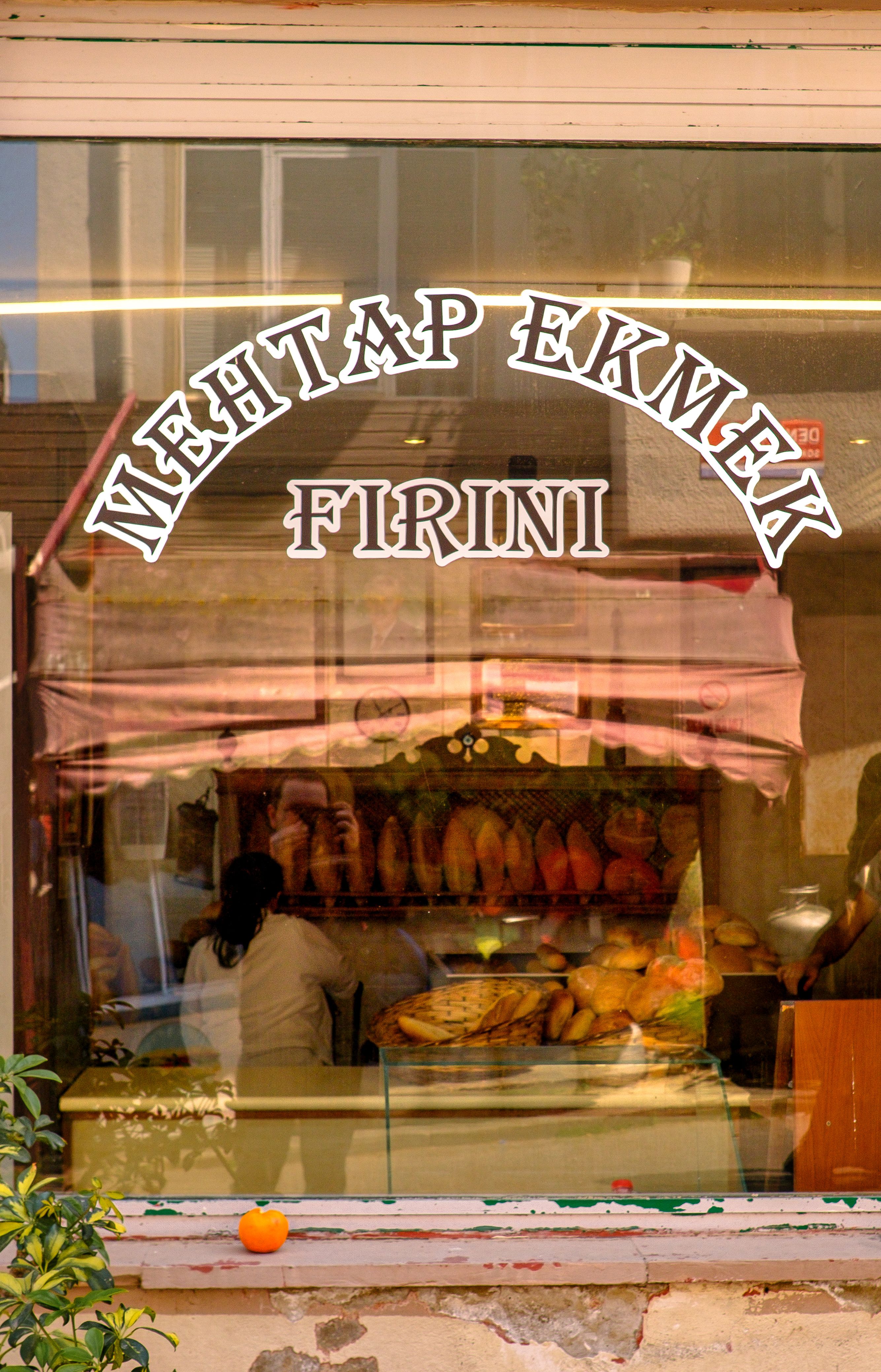 Charming bakery window showcasing fresh bread behind Turkish signage.