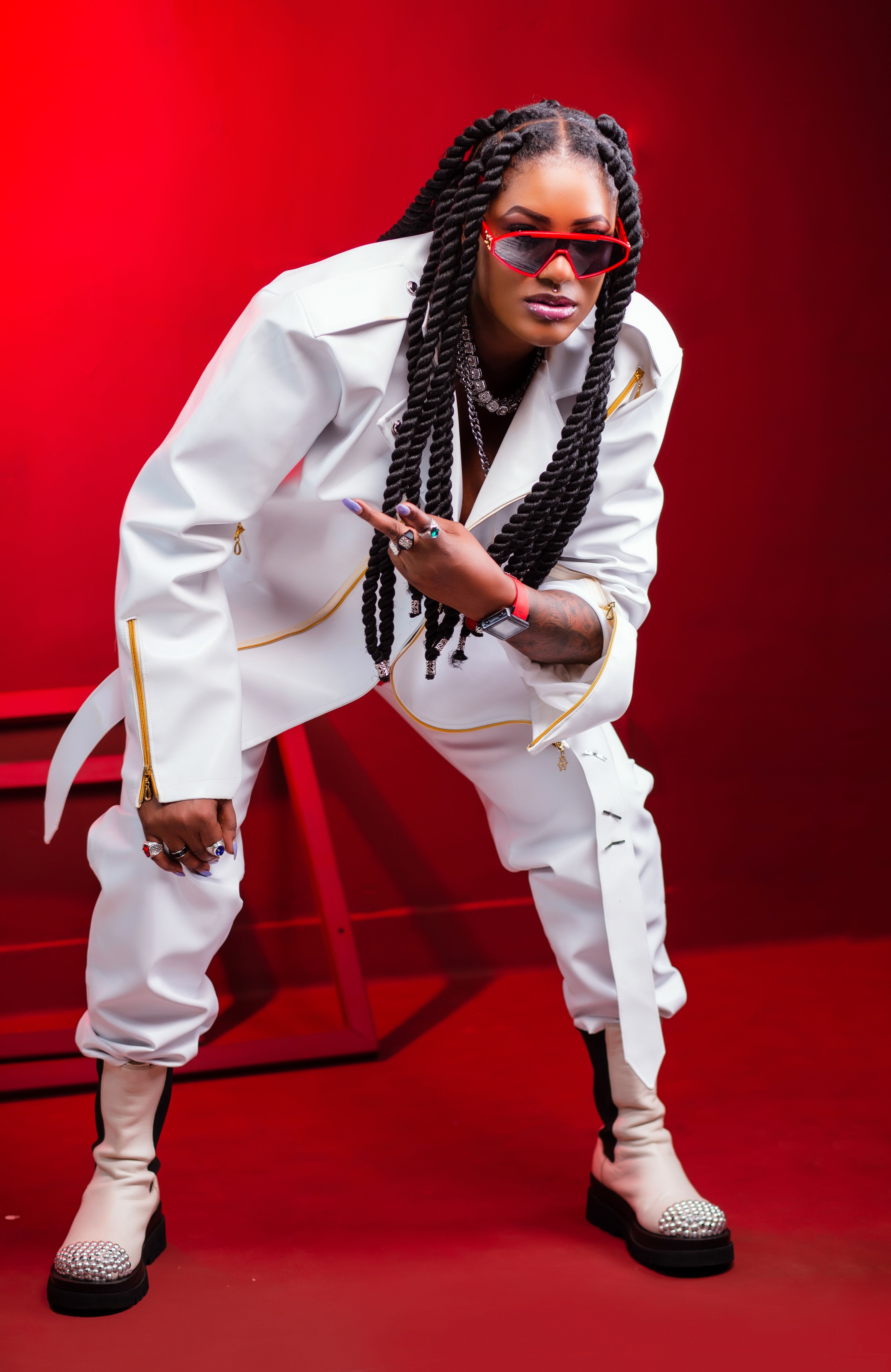 Confident woman in a white outfit and red background, showcasing modern fashion with attitude.