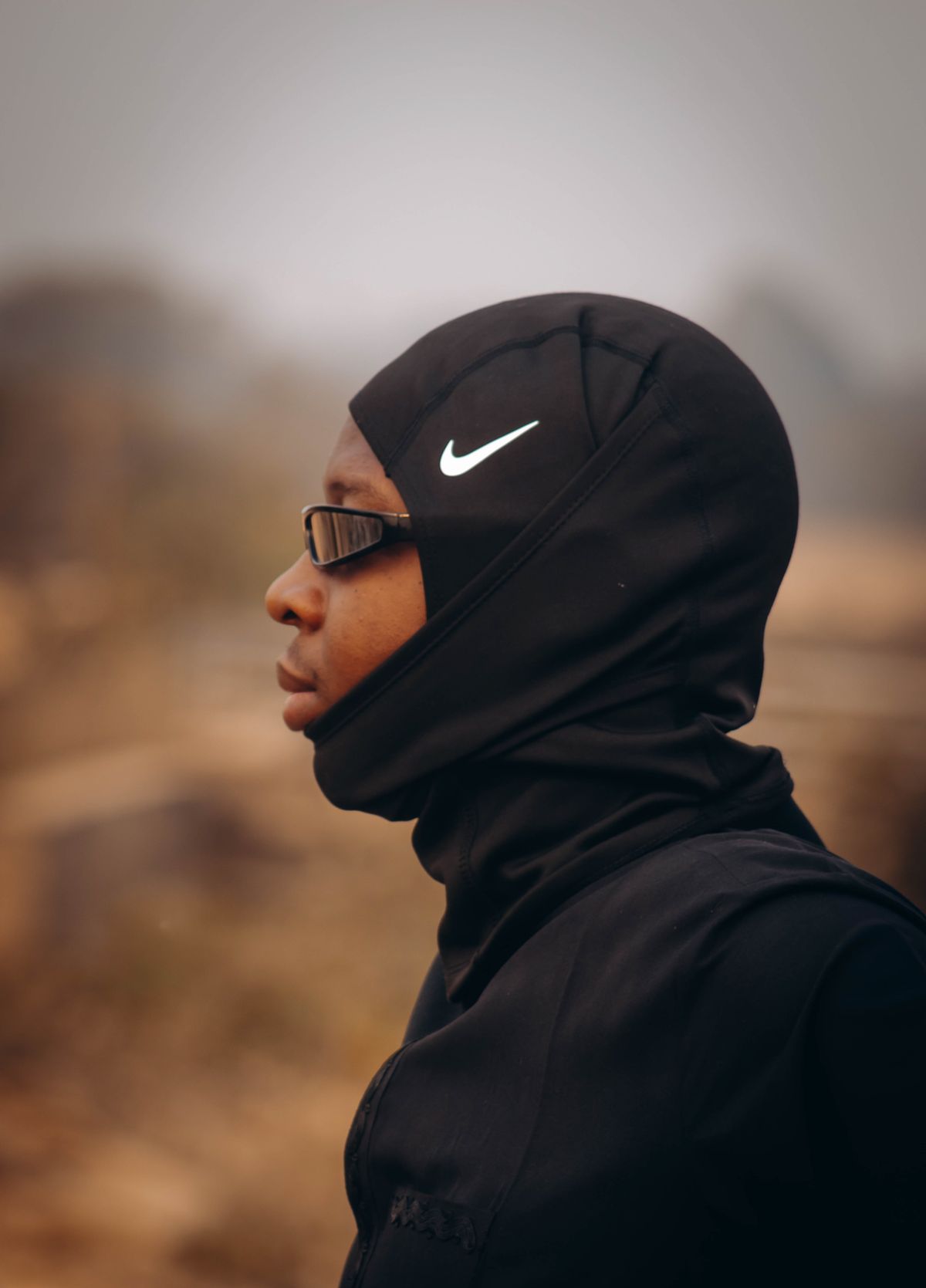 Athlete wearing black functional sportswear and a performance hoodie outdoors