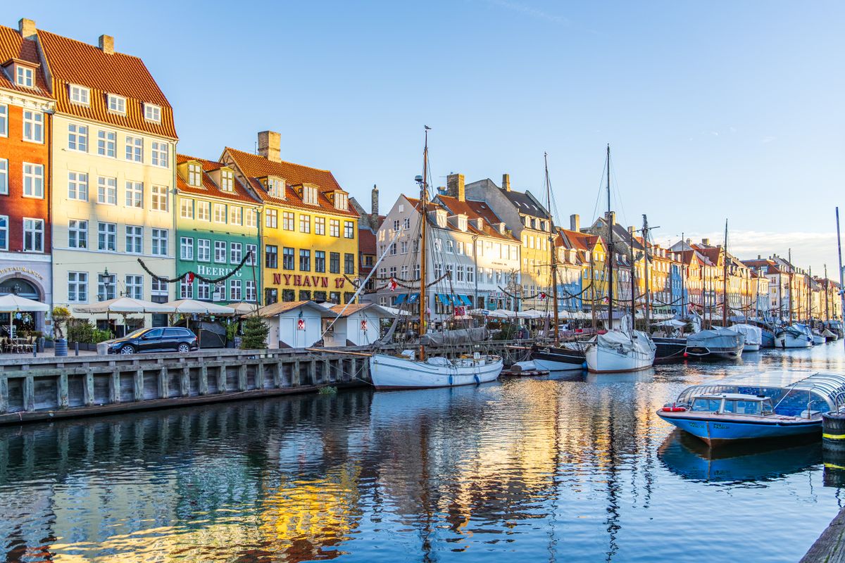 Unde te cazezi în Copenhaga - Nyhavn cu case colorate și corăbii vechi într-o zi senină