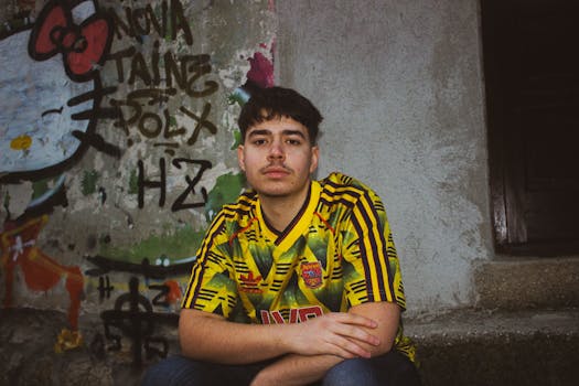 Casual portrait of a young man in a yellow jersey with colorful graffiti background.