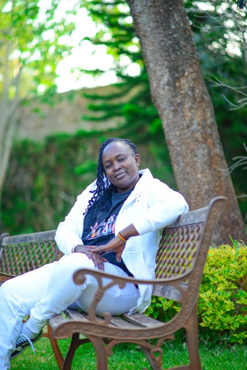 Free Person in white outfit relaxing on a park bench in a vibrant green garden. Stock Photo