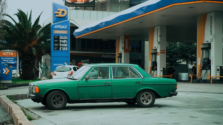 Classic green car parked at a gas station in Istanbul, Türkiye, under overcast weather.