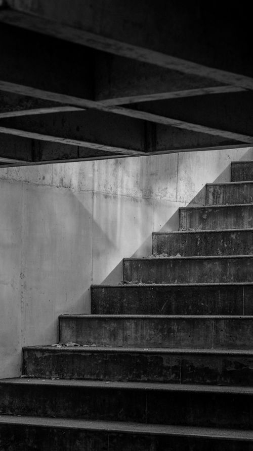 Free A striking black and white photo of staircase shadows creating geometric patterns. Stock Photo