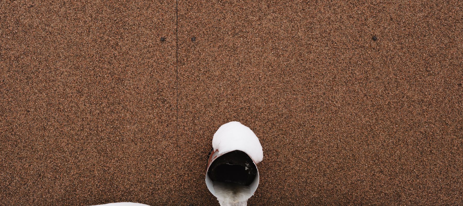Frozen water pipe against a wall in snow