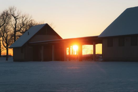 Snow-covered buildings at sunrise creating warm contrast in winter landscape.